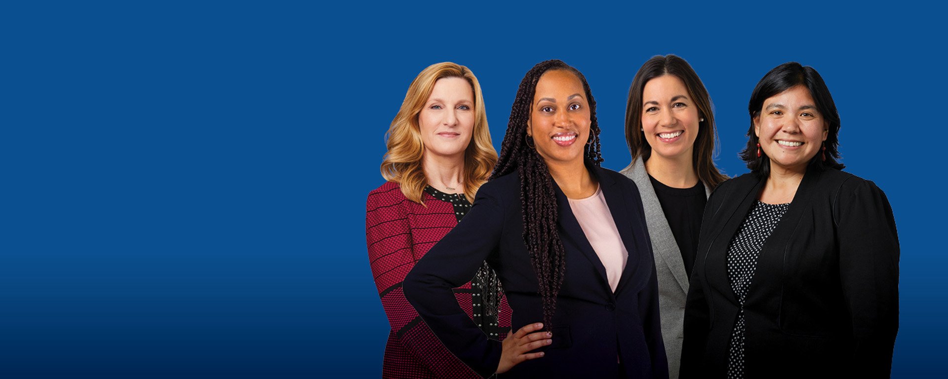Four professional women posed as a group with a blue background.