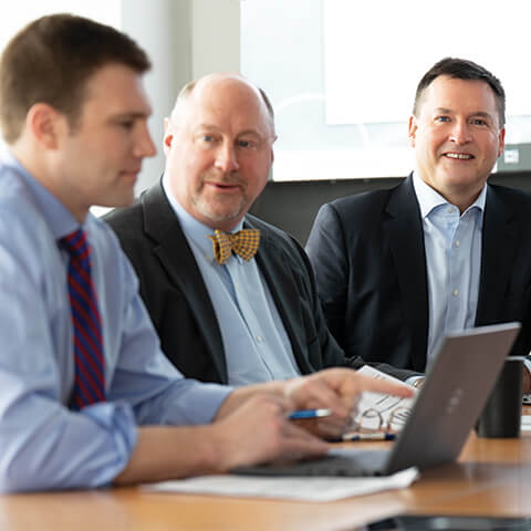 Candid photo of three men working in a conference room