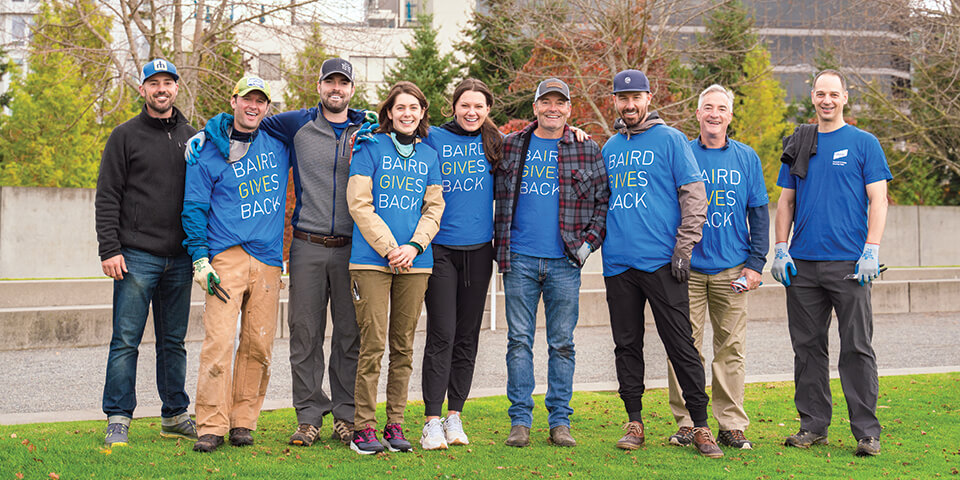 A photo of nine Baird associates wearing Baird Gives Back t-shirts while cleaning a park