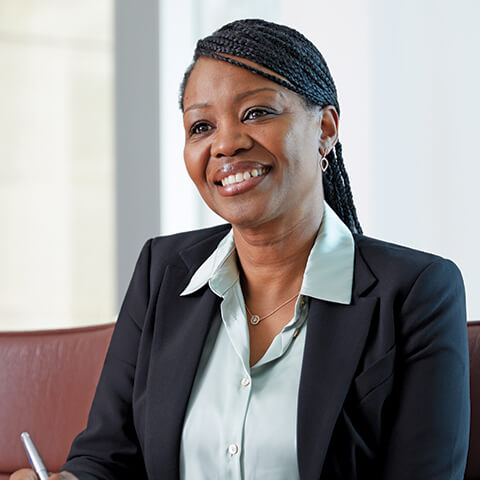 Photo of a smiling woman taking notes at a conference room table