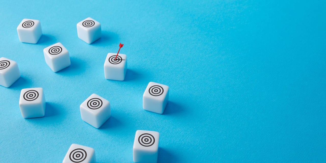 Ten white dice with bullseye images on them scatted on a blue surface.