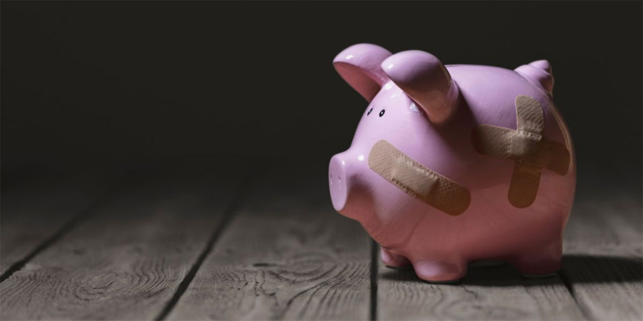 Pink ceramic piggy bank with band aids on the face and side.