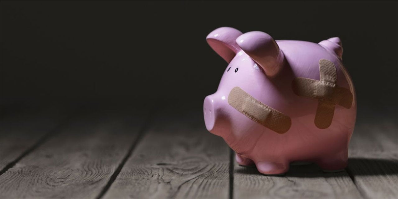 Pink ceramic piggy bank with band aids on the face and side.