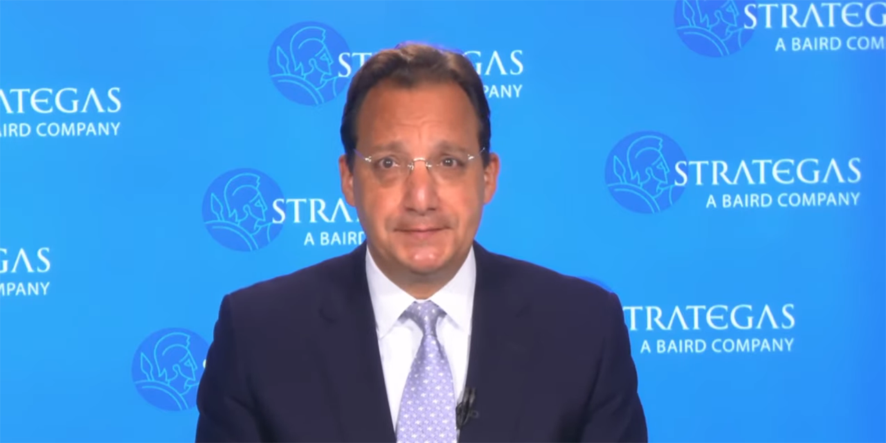 Strategas Chairman and CEO Jason Trennert against a blue, Strategas branded background