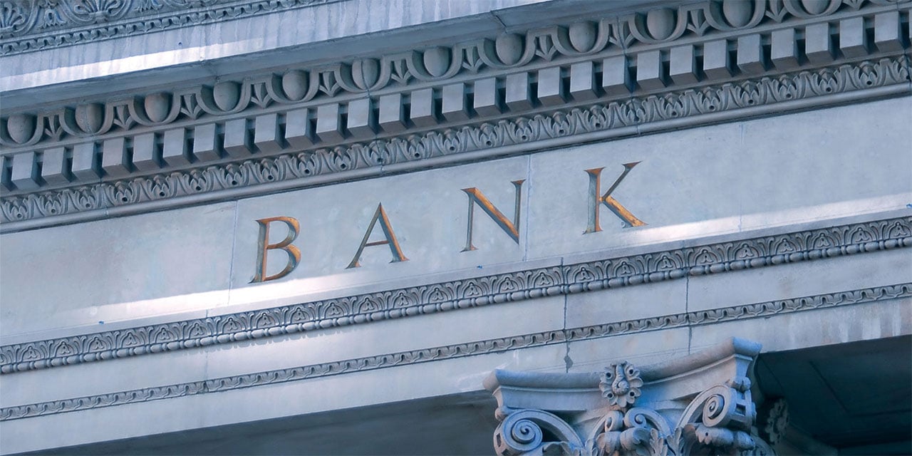 Front of a bank showing the word 'bank" etched into stone.