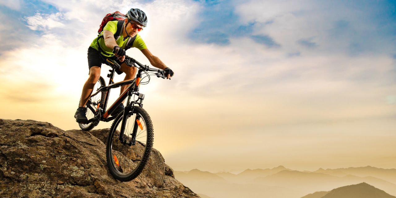 Man riding a mountain bike on a hill at sunset