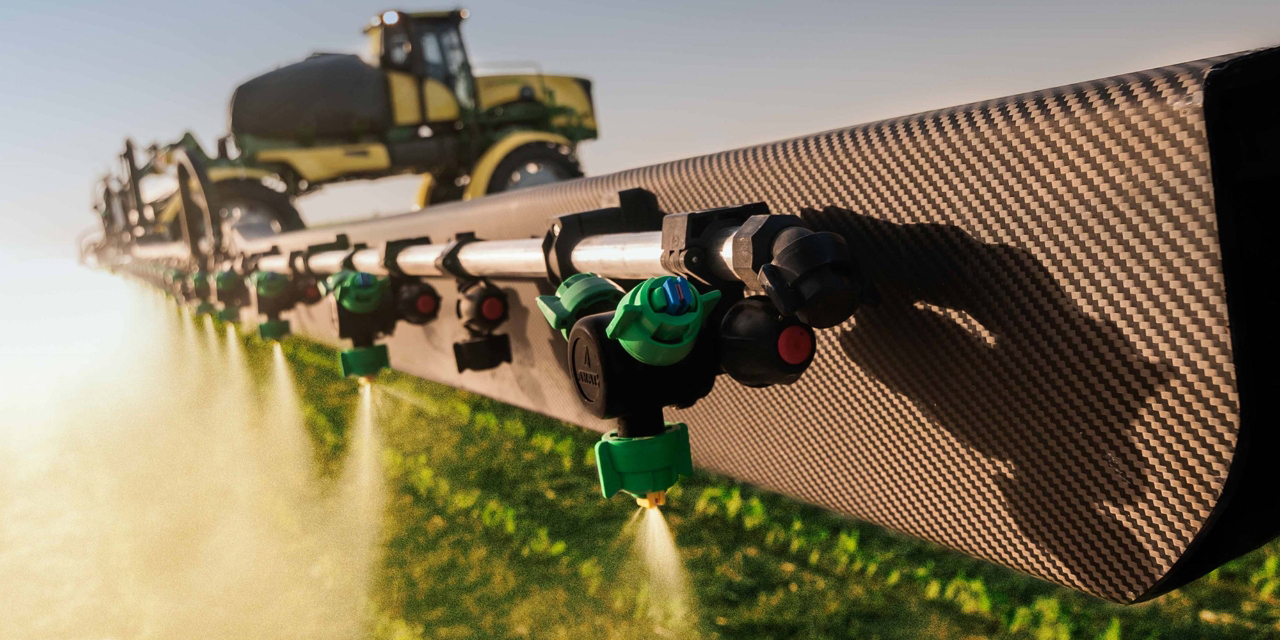 Close up image of a farm field sprinkler system with a tractor in the background.