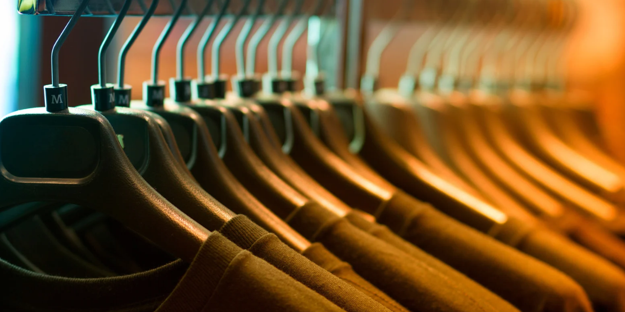 T-shirts handing on a clothing rack on wooden hangers.