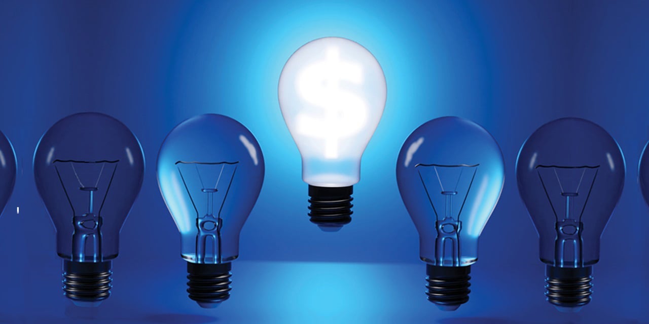 Bright white light bulb with dollar sign stands out among dim blue bulbs on a blue background.