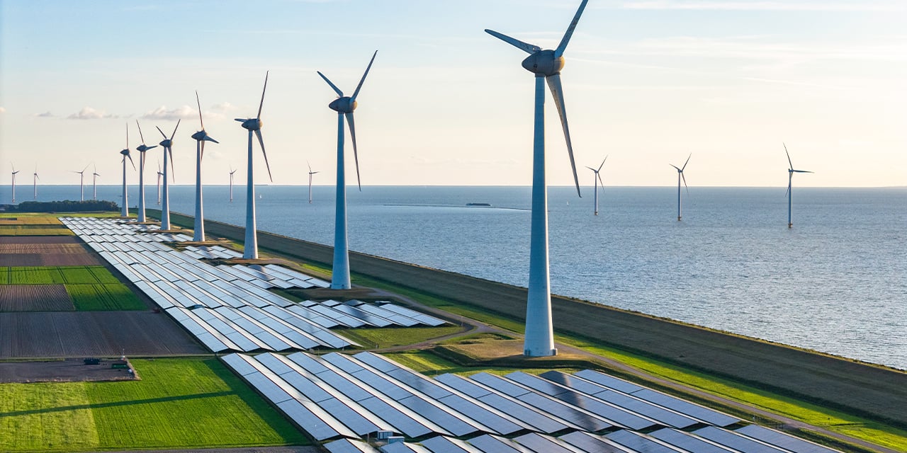 Windmills in a field next to a body of water