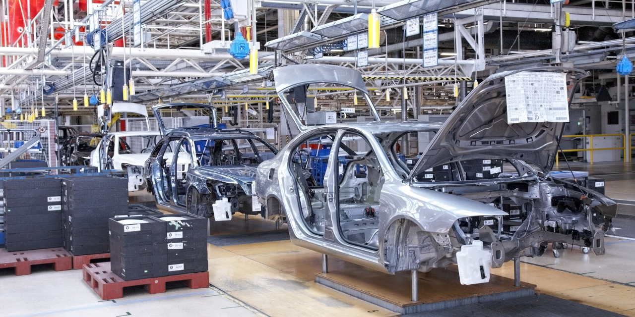 Automotive assembly line with unfinished car bodies moving through a modern manufacturing facility.