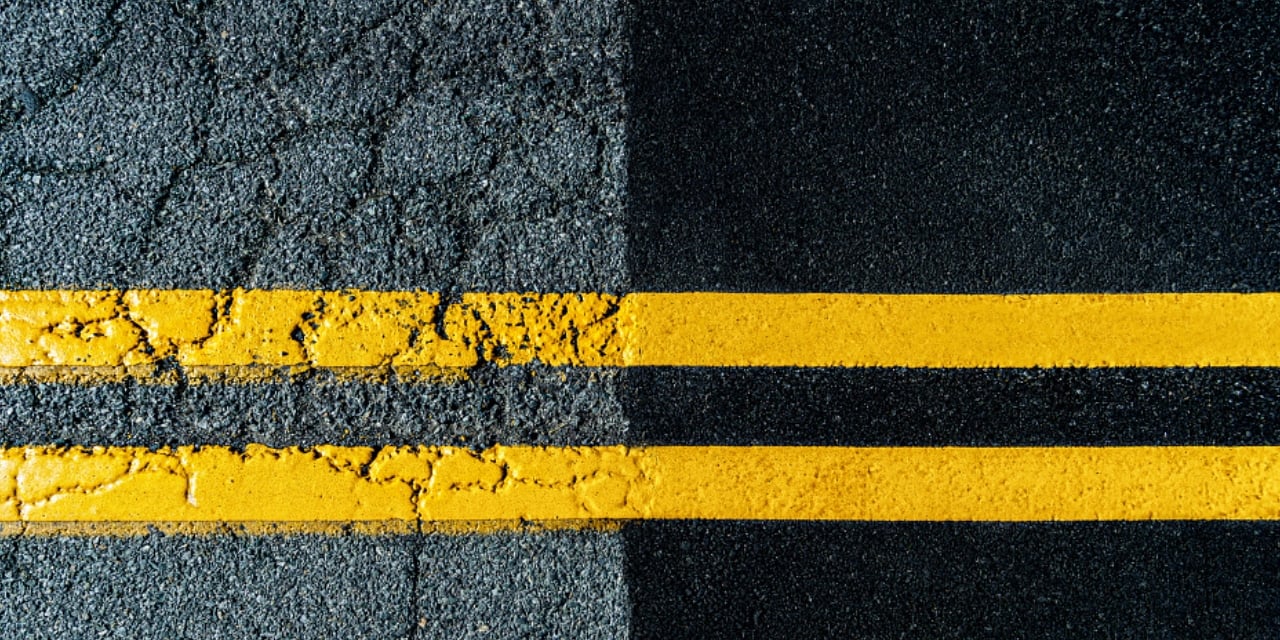 Close view of a blacktop road with one side in good condition and the other in poor condition.