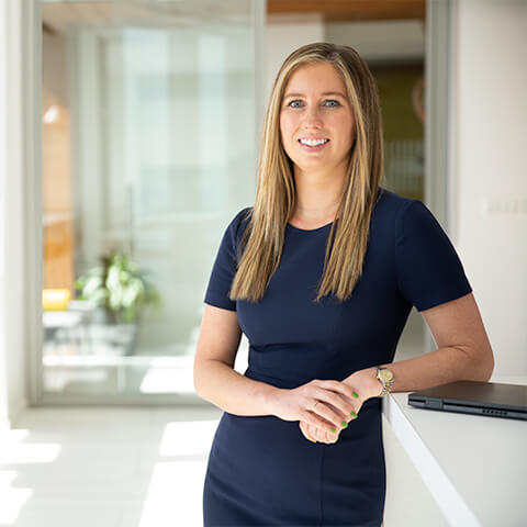 A photo of a smiling woman next to a table in an office area