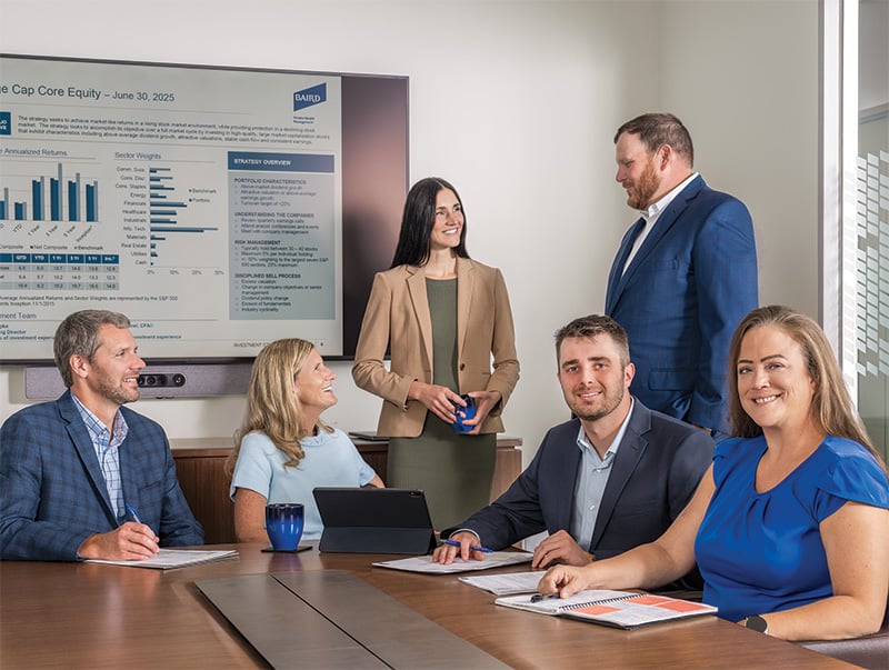 Associates from Baird Private Wealth Management sitting around a conference table with a presentation in the background