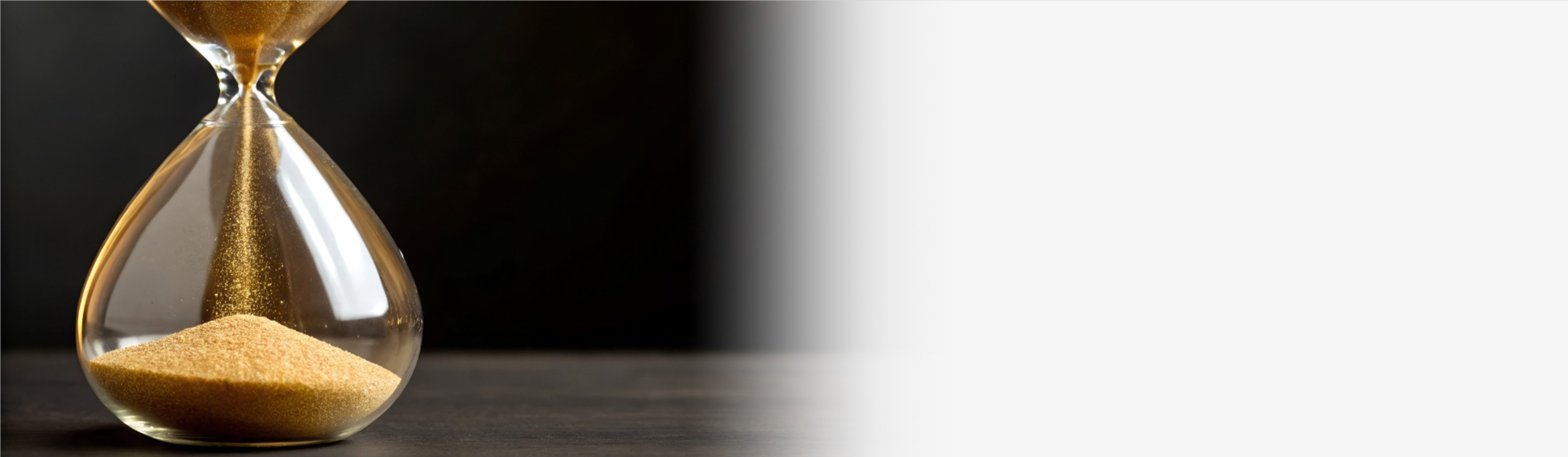 An hour glass with a black background, fading to white on the right side of the image.