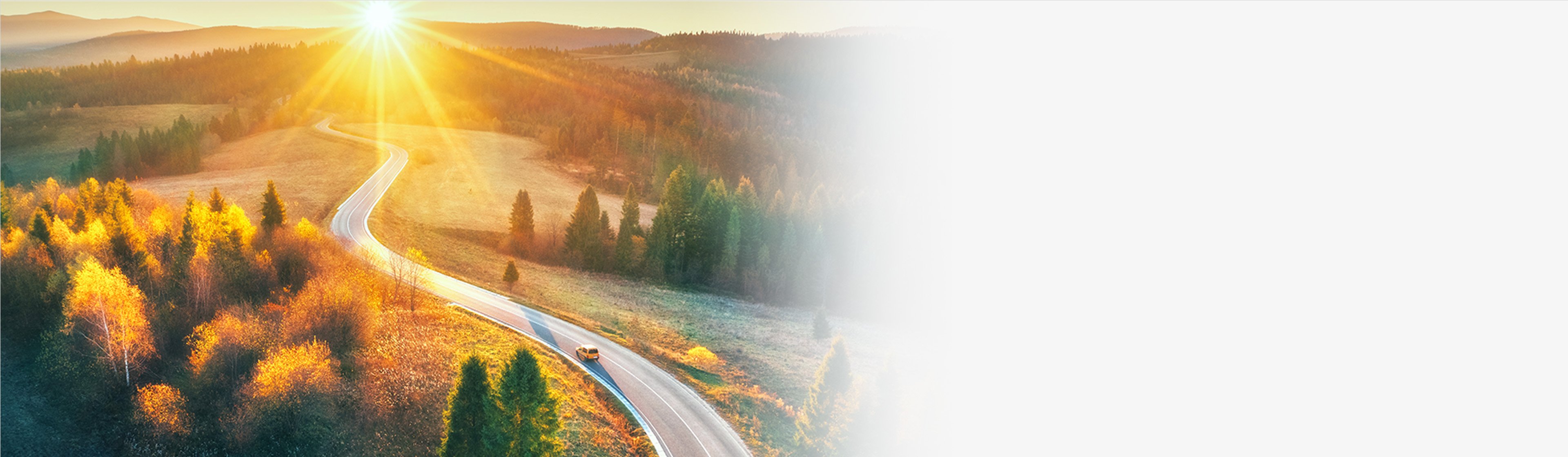 Sunlit winding road through autumn hills and forests, suggesting a forward-looking financial journey.