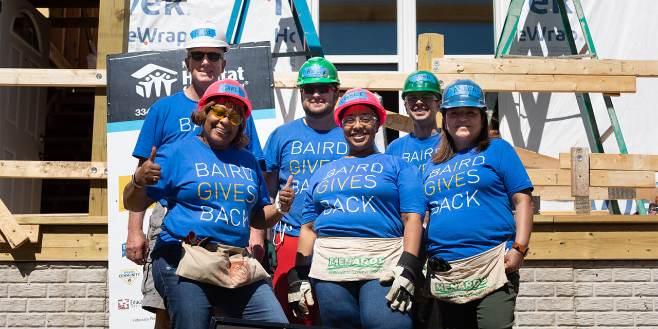 Baird associates in "Baird Gives Back" shirts volunteer building a home with Habitat for Humanity