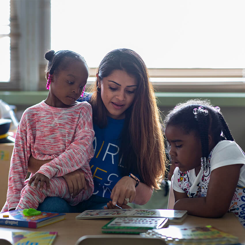 A Baird associate reads to two young children at a Baird Gives Back event at NextDoor Milwaukee