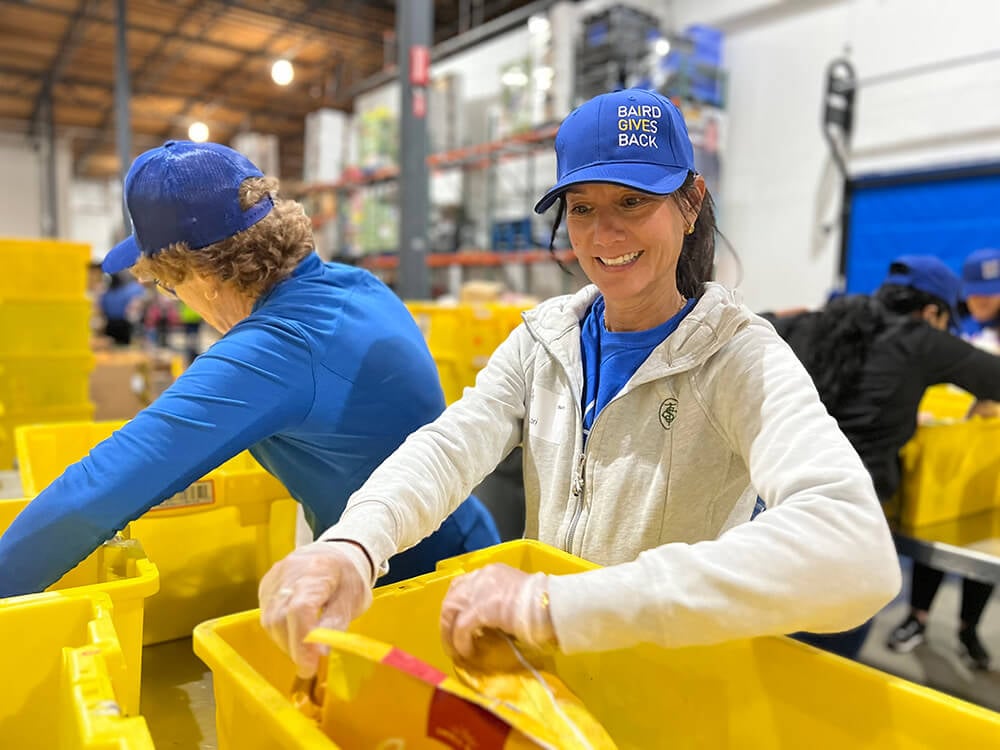 Two Baird associates sort food into bins at Food Lifeline in Seattle