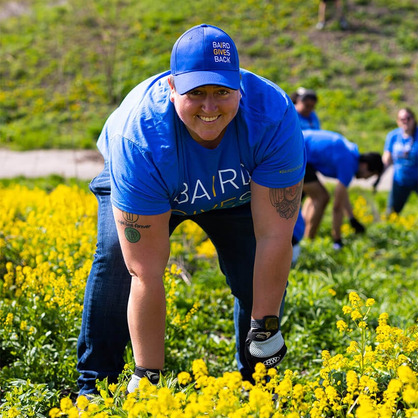An individual is in a field of yellow flowers volunteering. 