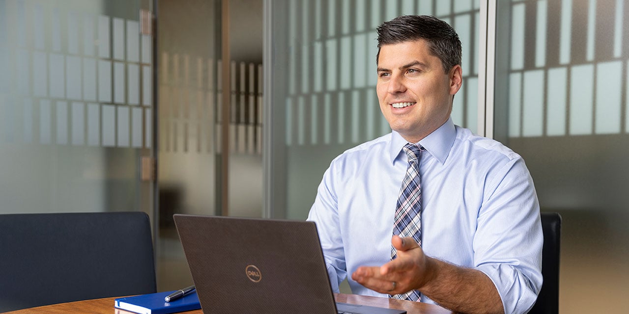 Man wearing a shirt and tie looking at a laptop