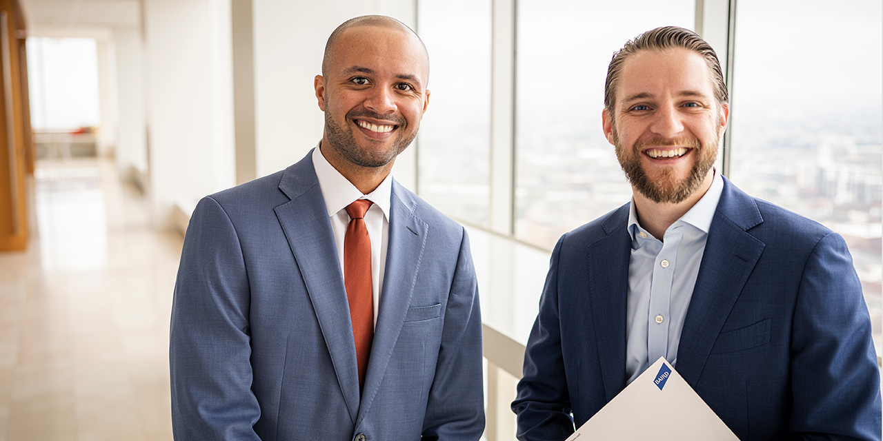 Two professionals standing in an office hallway.