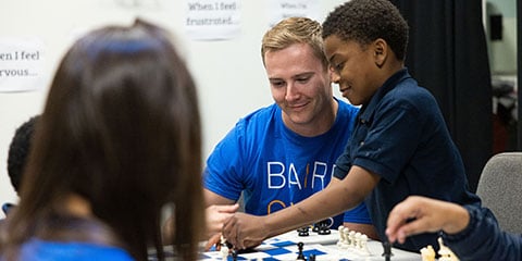 Baird associate and children playing chess.