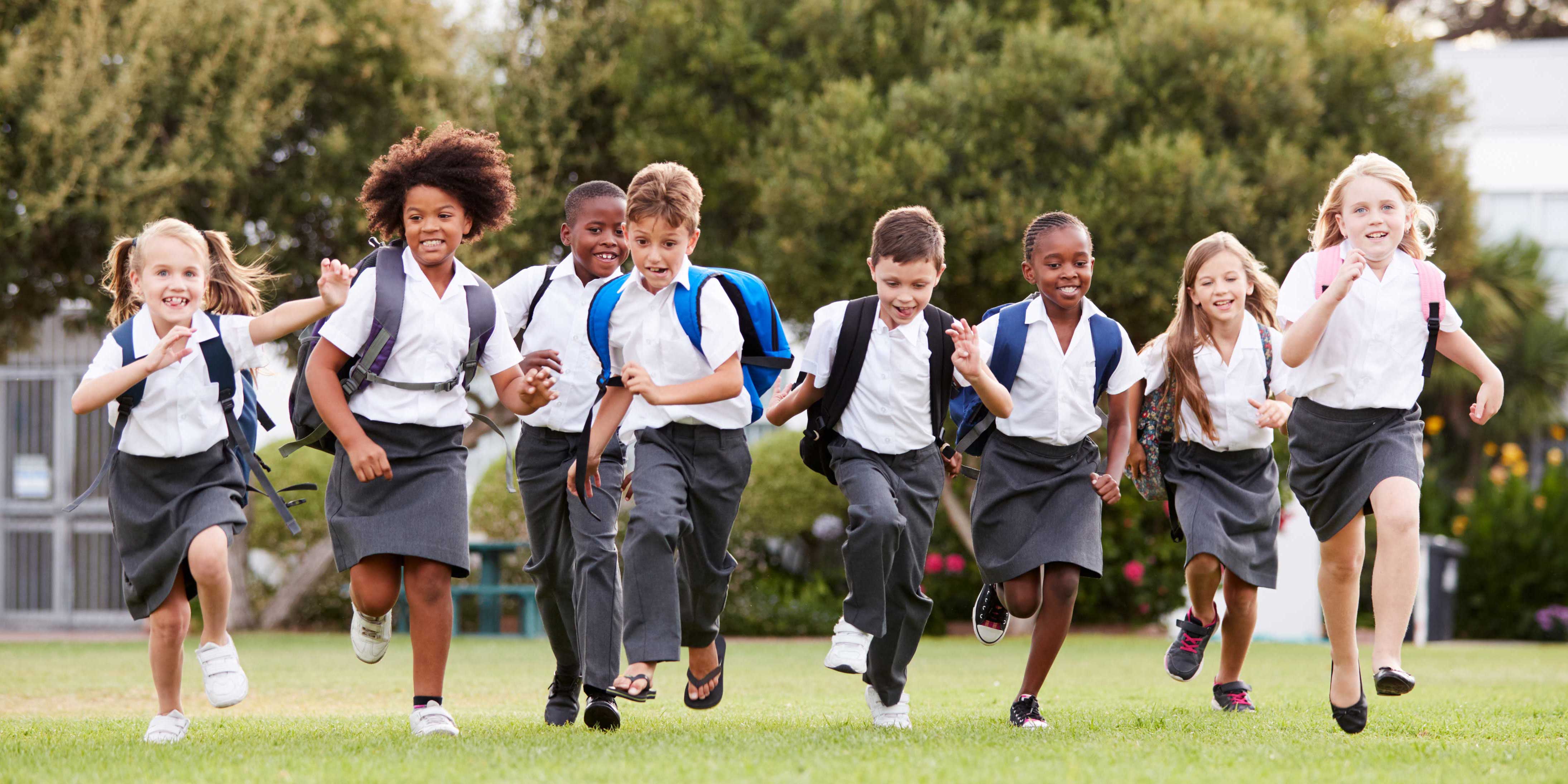 School kids running through a park