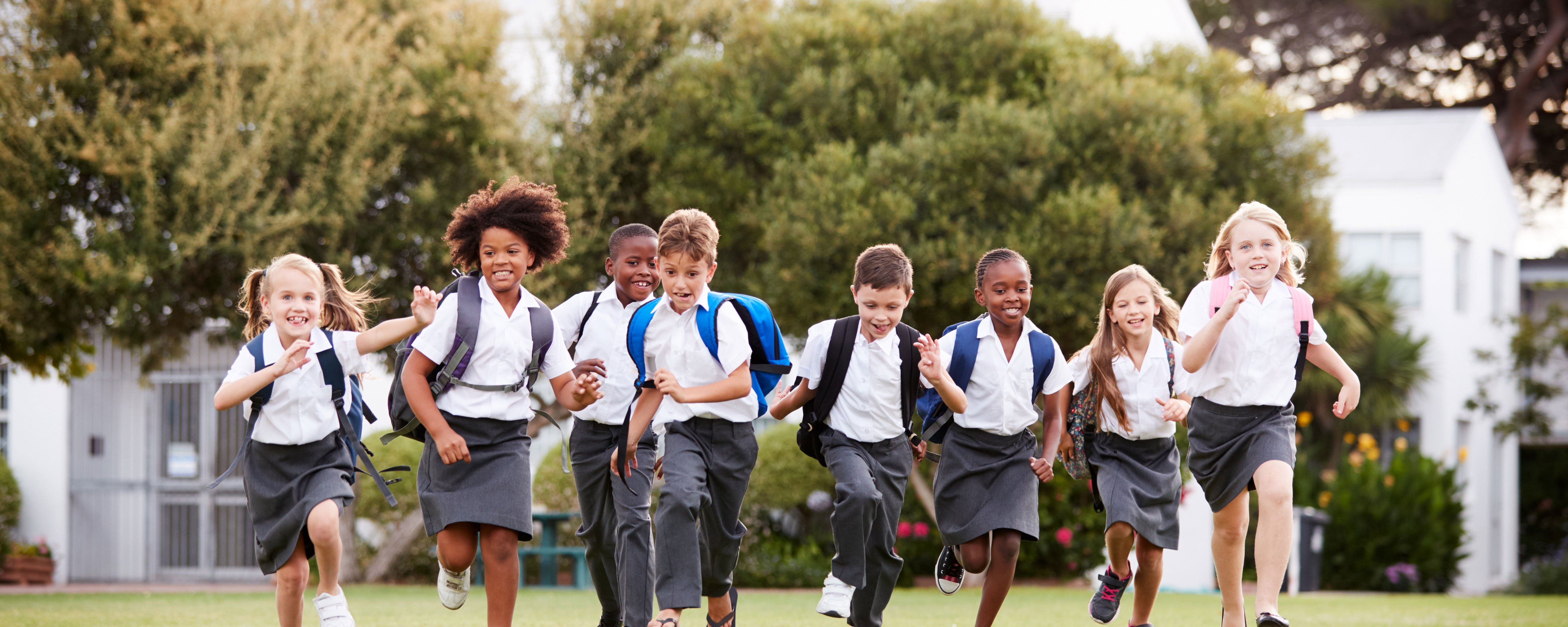 School children running in a park wearing uniforms