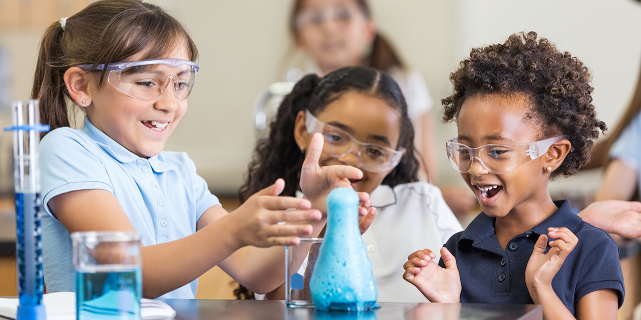 Three elementary students doing a chemistry experiment using a beaker.