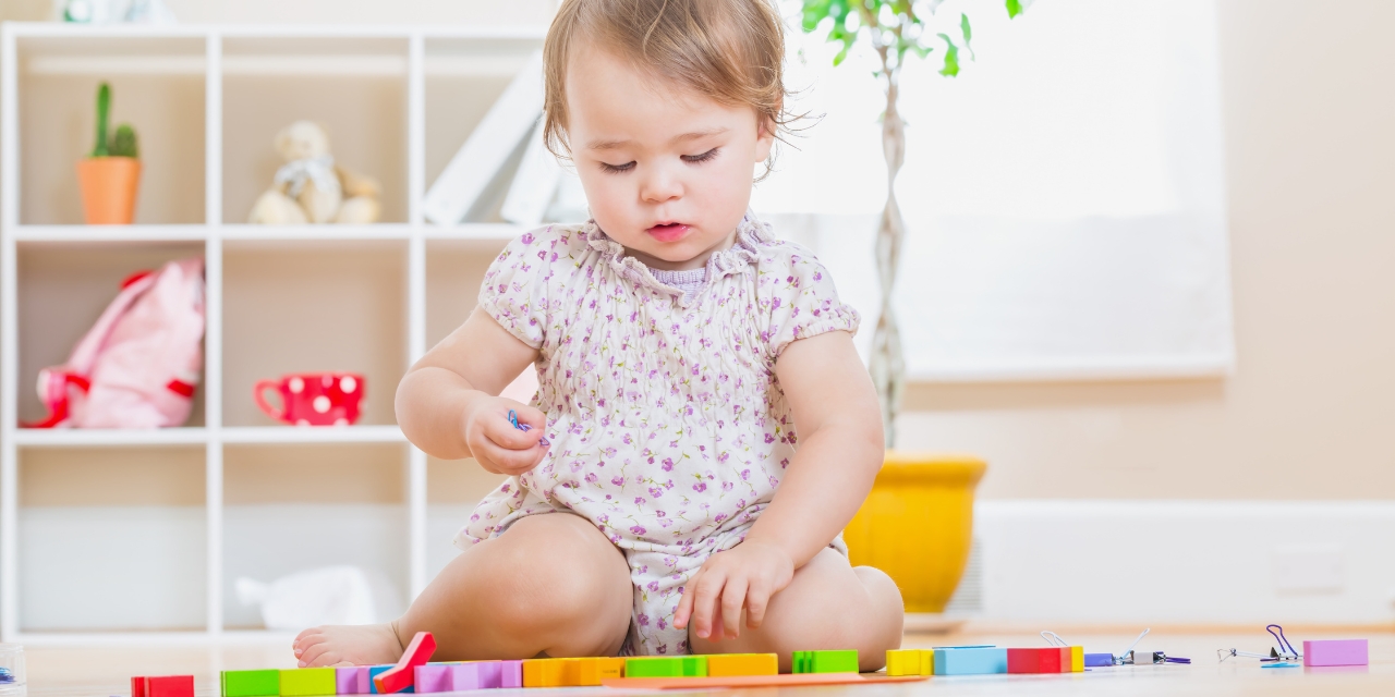 Toddler sitting on floor playing with blocks