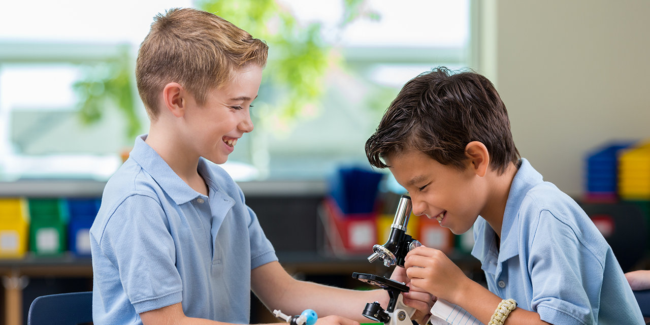 Two elementary school students using a microscope