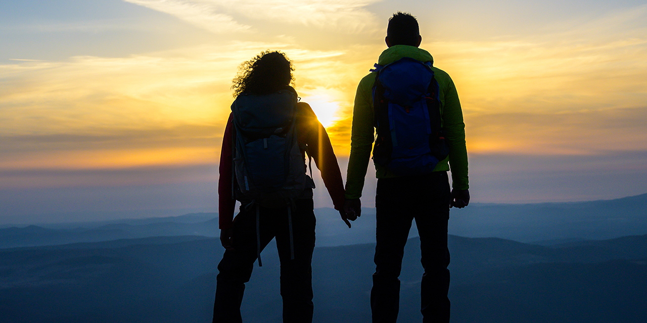 Couple standing on a mountain top.