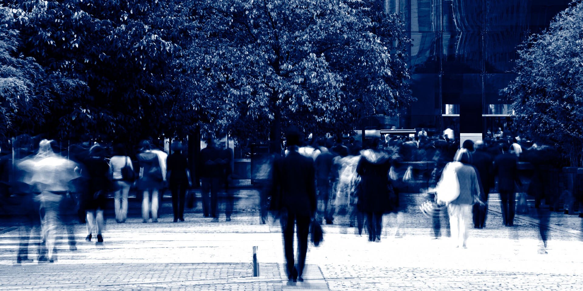 Blurred black and white images a professionally dressed people walking down a sidewalk.