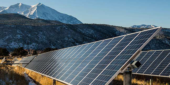 Rows of solar panels in a valley with mountains the background