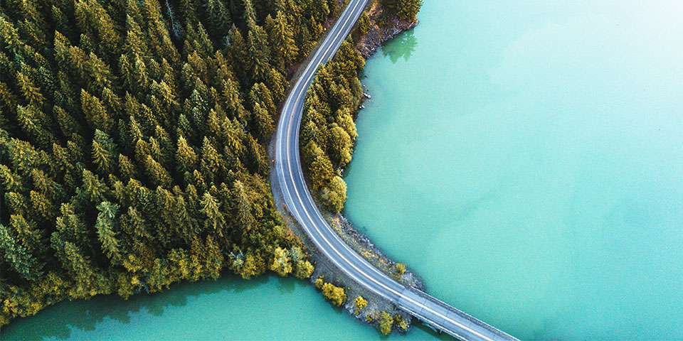 Overhead shot of road winding through lake and forest