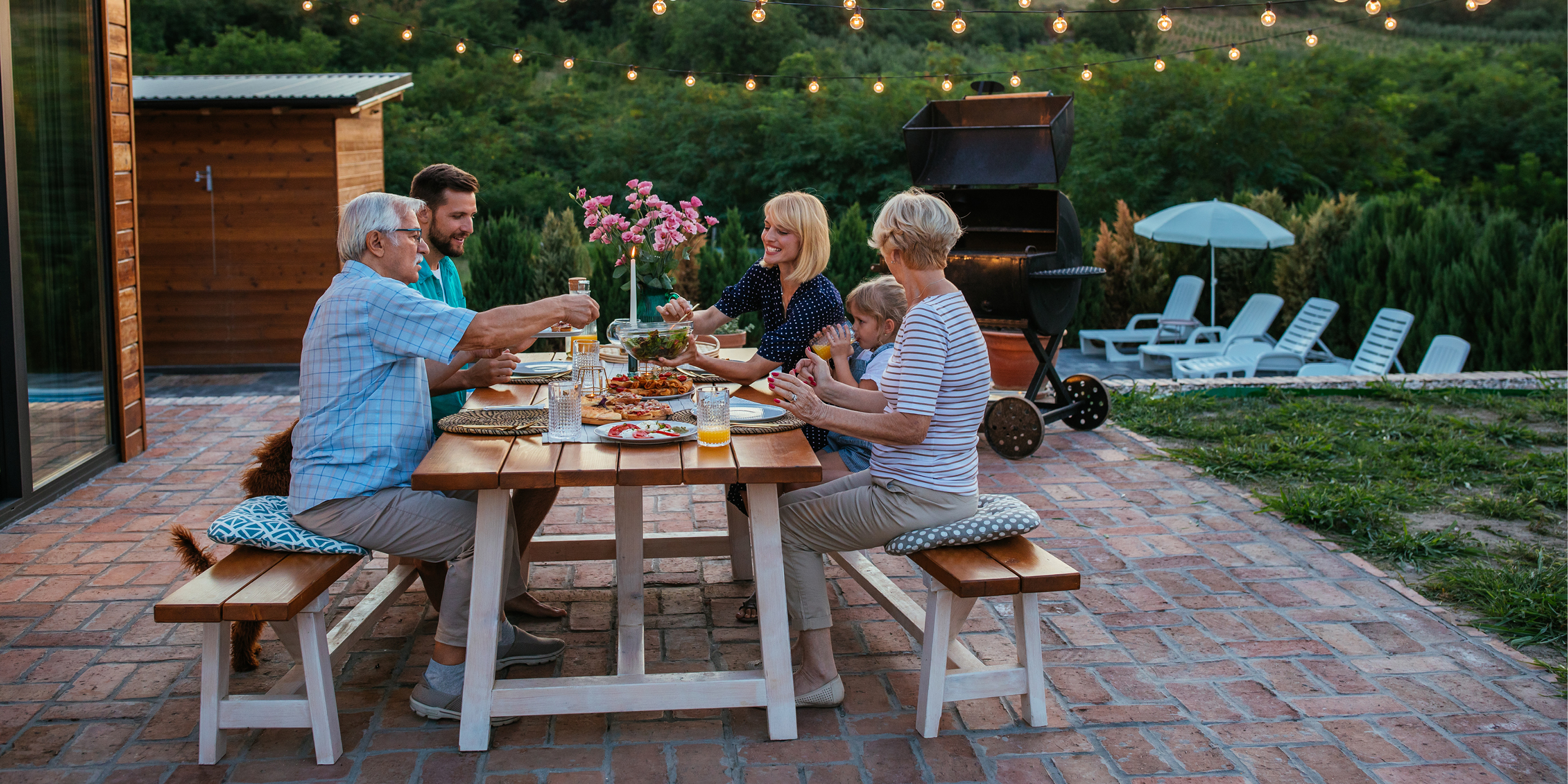 Multigenerational family eating dinner at an outdoor table.