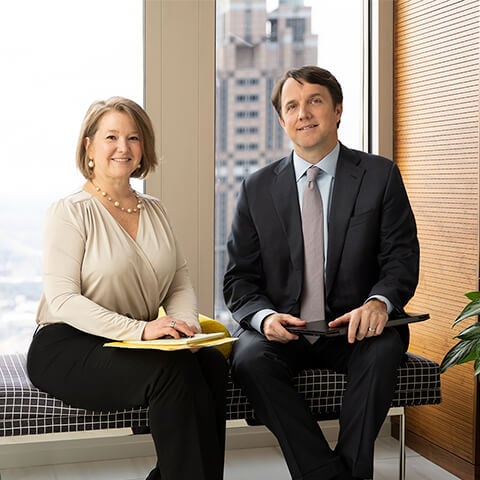 An image of a woman and man sitting on a bench in an open office area