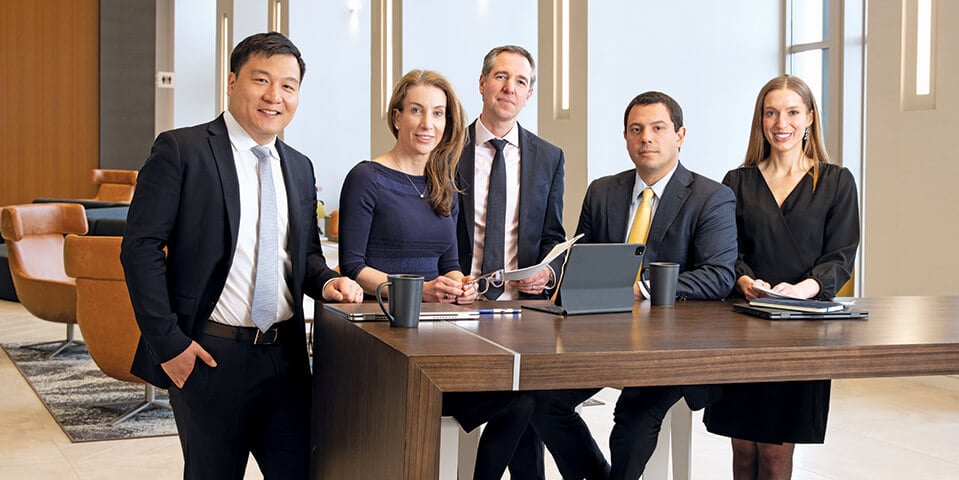 A photo of five associates working at a table in an open office area