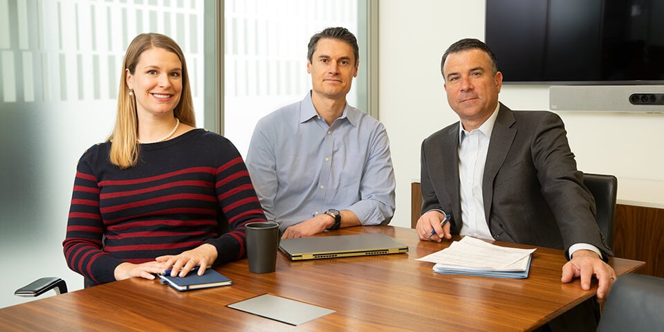 Three smiling Principal Investment associates working in a conference room