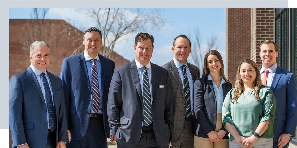 An image of the Dayton Private Wealth Management team smiling as they stand outside of their office