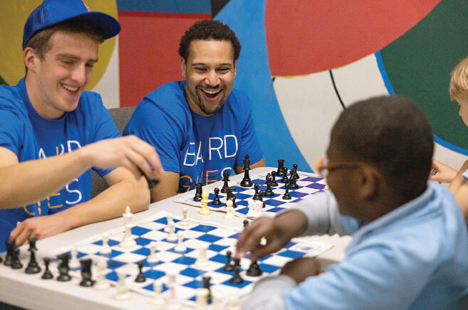 Two Baird associates playing chess with children at the Chicago Chess Foundation