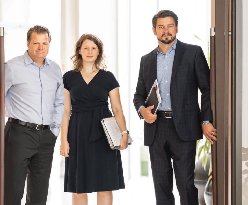 Three Equity Capital Markets associates stand in a doorway