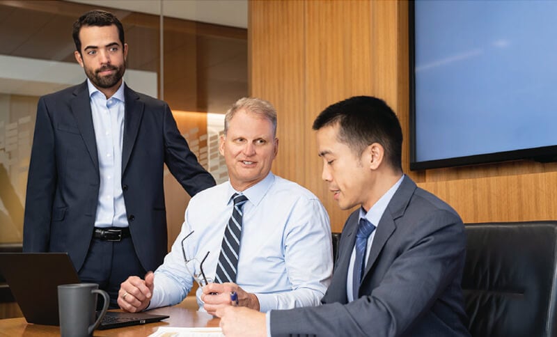 Three Fixed Income Capital Markets associates meeting in a conference room
