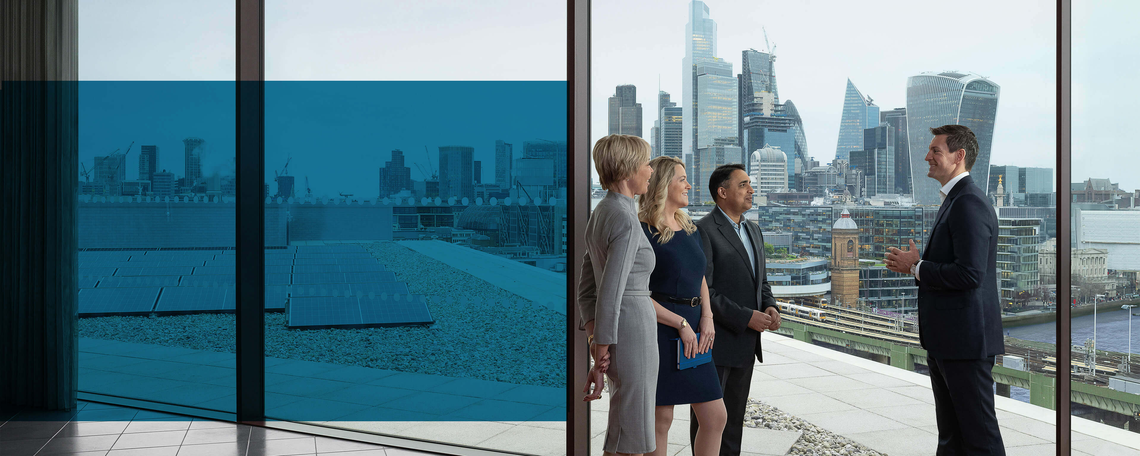 Four Baird associates conversing near a large window in the London office overlooking the London skyline