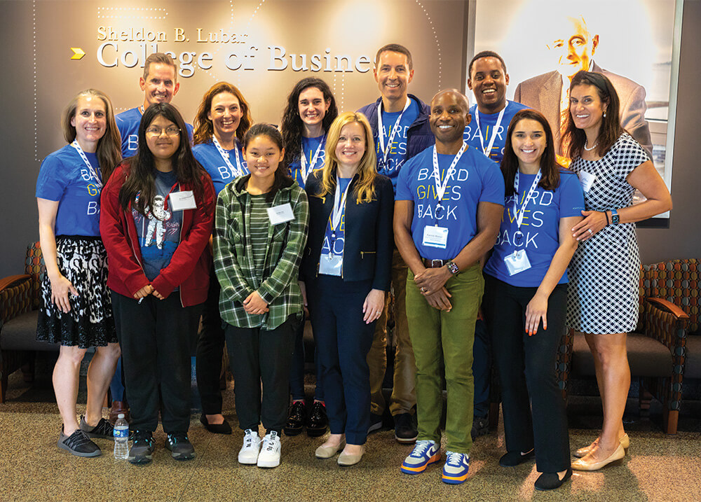 A group of Individuals pose as they visit the Sheldon B. Lubar School of Business.