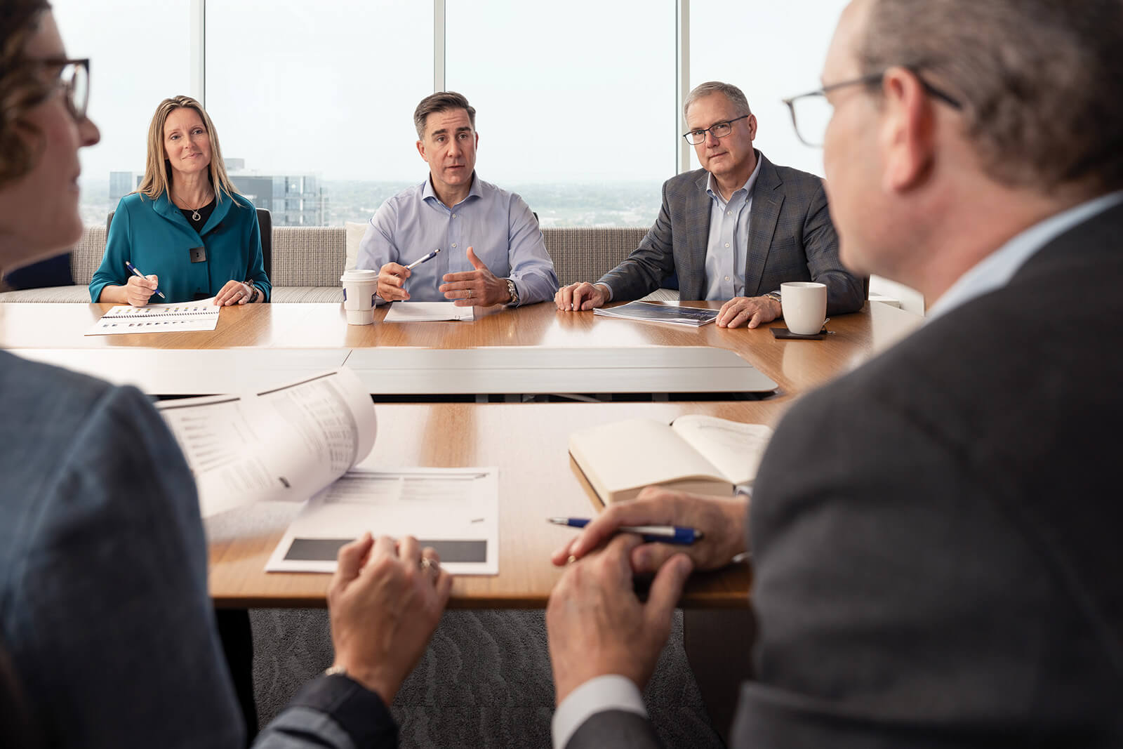 Five associates from Baird's Private Wealth Management team discussing around a conference room table