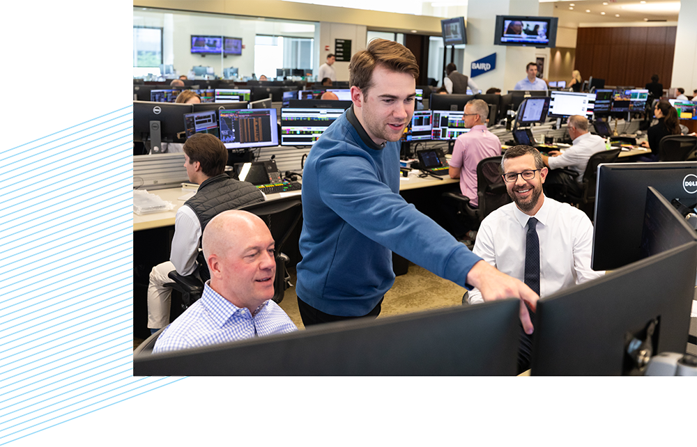 Three Baird associates looking at computer monitors on the trading floor