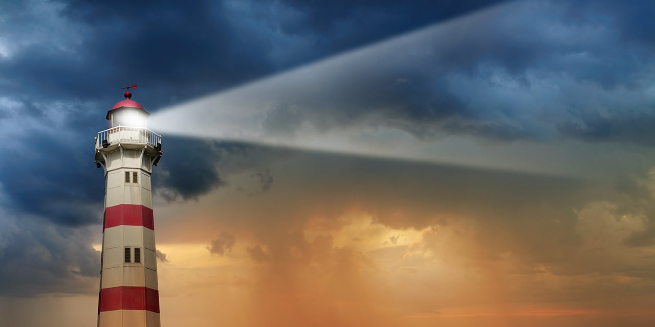 Lighthouse with clouds and sunset in the background.