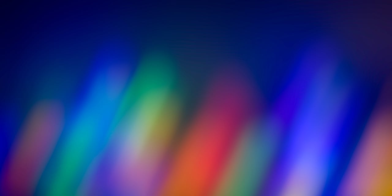 Blurred streaks of colorful light against a dark background creating an abstract gradient effect.